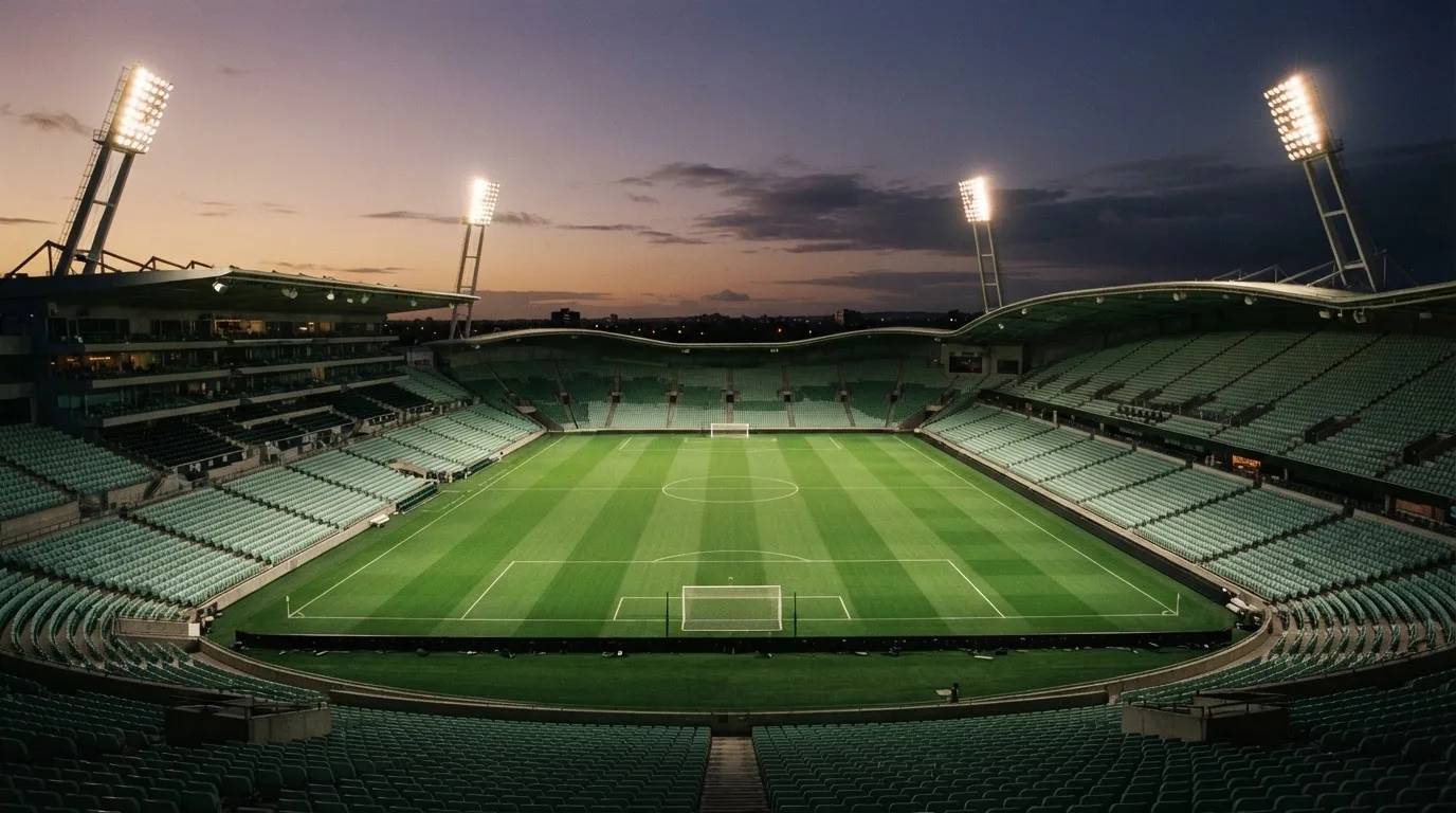An empty football stadium with floodlight masts at dusk