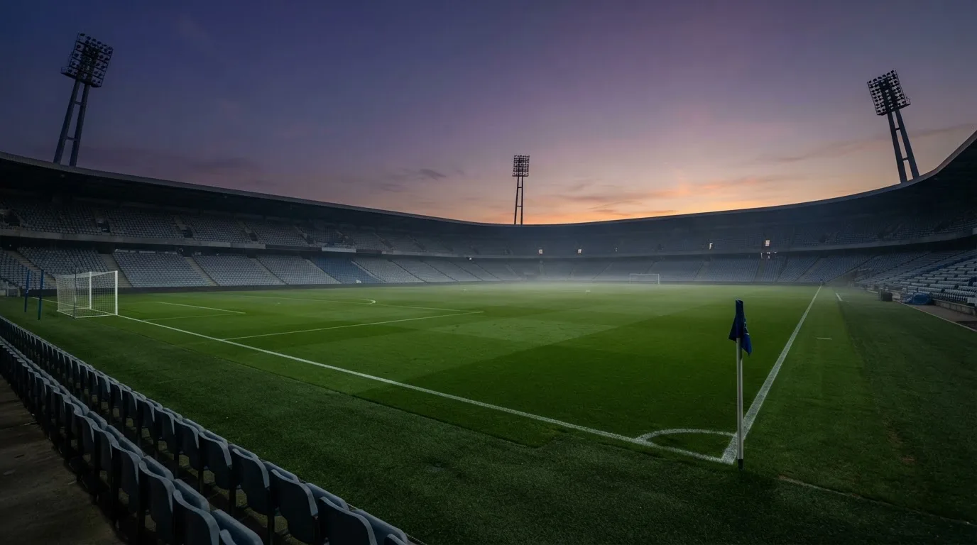 An empty football stadium with floodlight masts at dusk