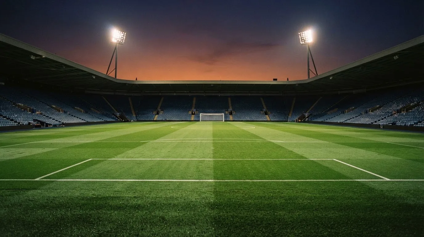 An empty football stadium with floodlight masts at dusk