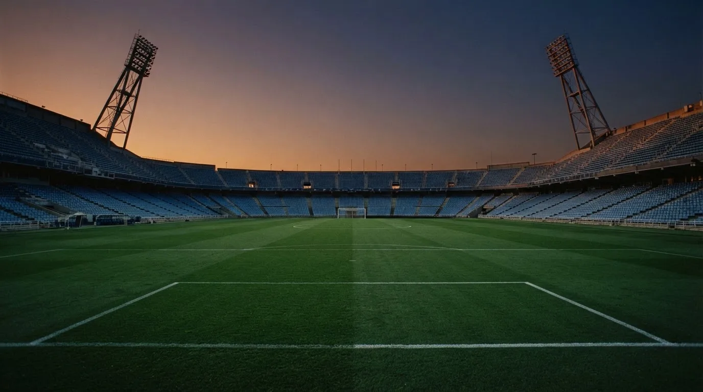 An empty football stadium with floodlight masts at dusk