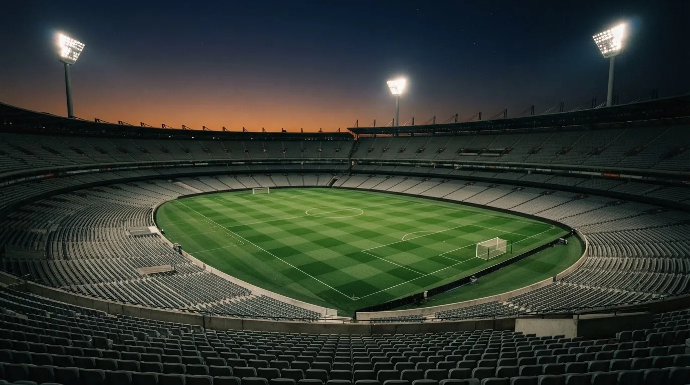 An empty football stadium with floodlight masts at dusk