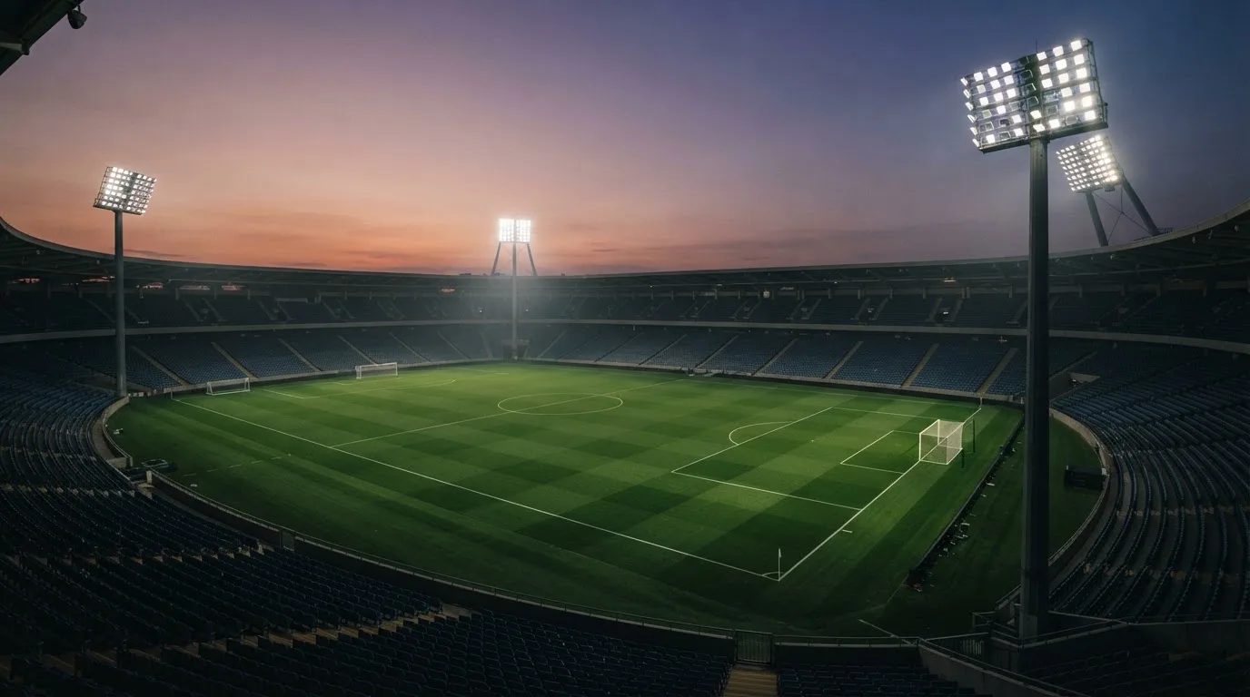 An empty football stadium with floodlight masts at dusk