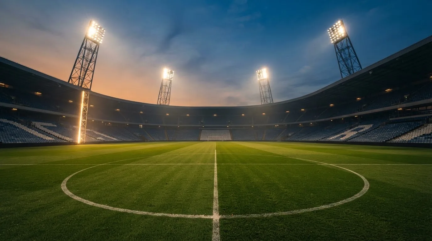 An empty football stadium with floodlight masts at dusk