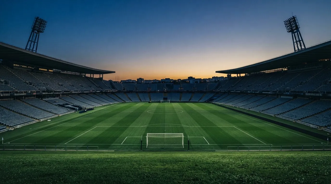 An empty football stadium with floodlight masts at dusk