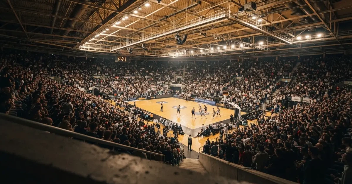 A packed sports hall under floodlights photographed from a long way off