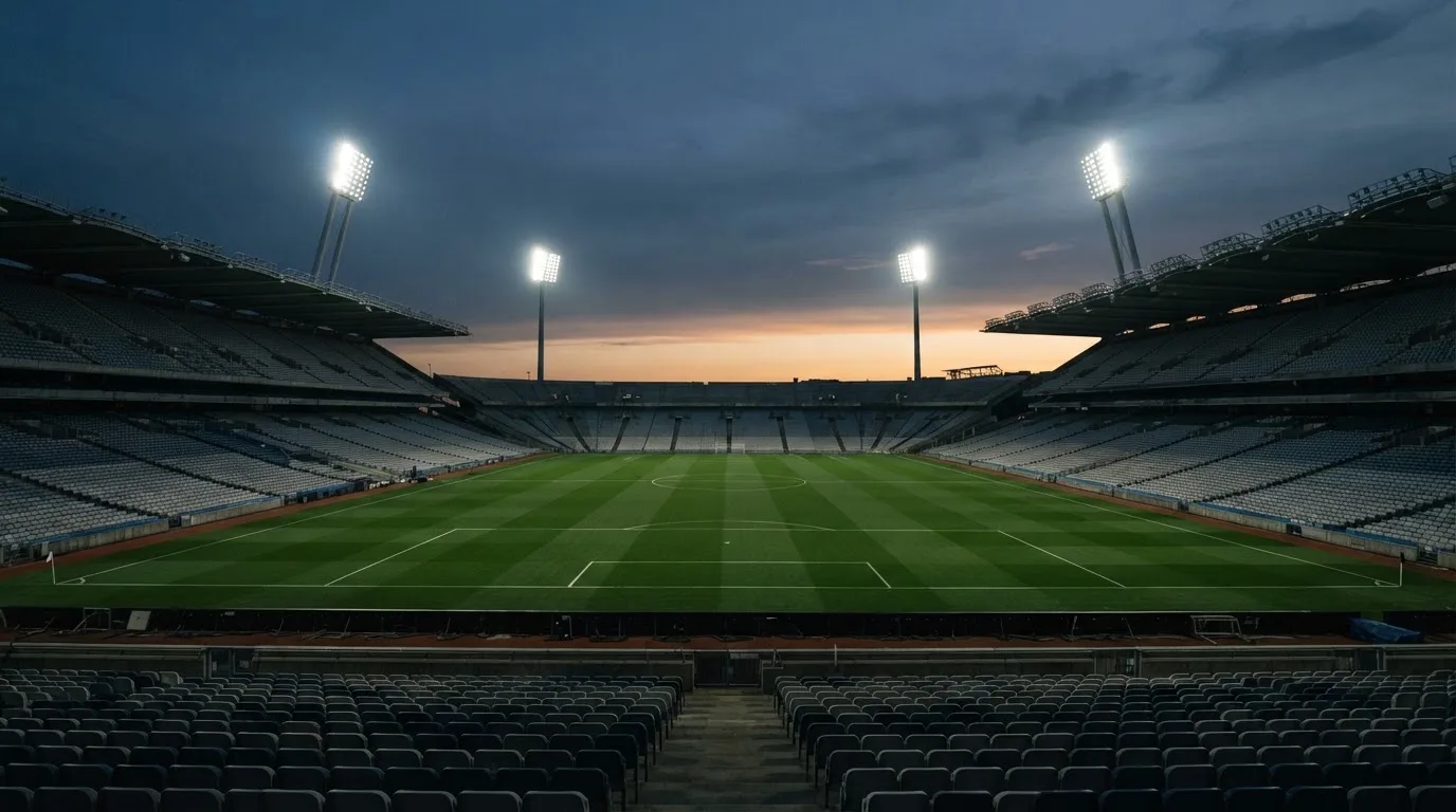 An empty football stadium with floodlight masts at dusk