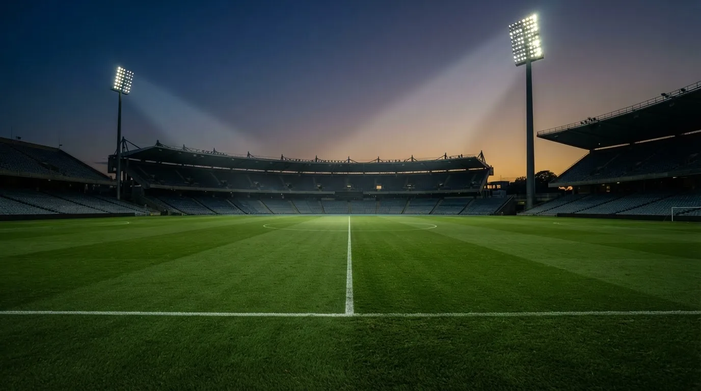 An empty football stadium with floodlight masts at dusk