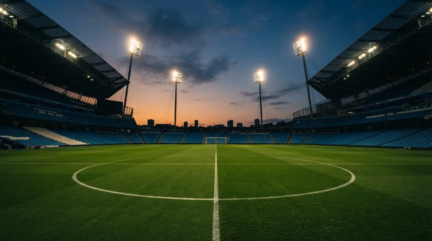 An empty football stadium with floodlight masts at dusk