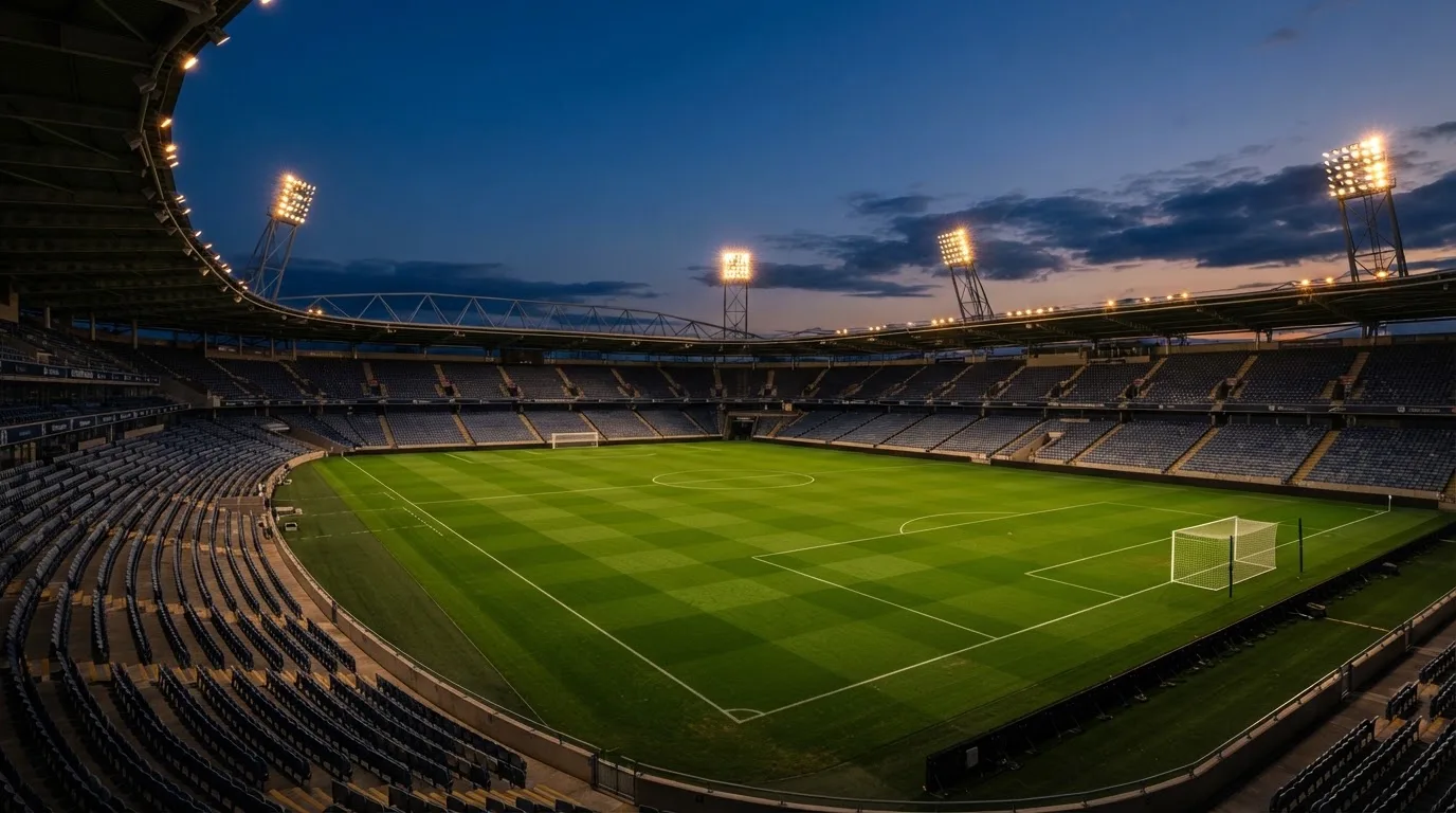 An empty football stadium with floodlight masts at dusk