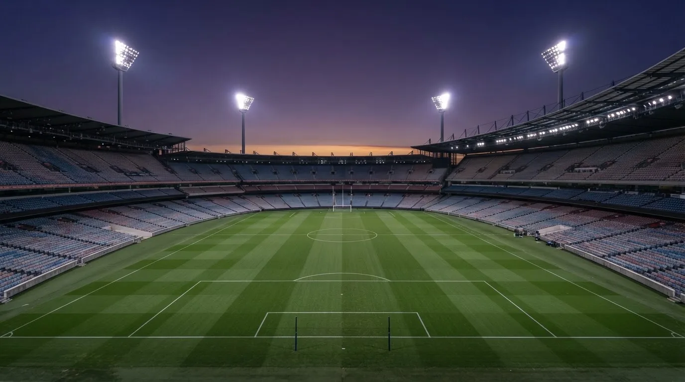 An empty football stadium with floodlight masts at dusk
