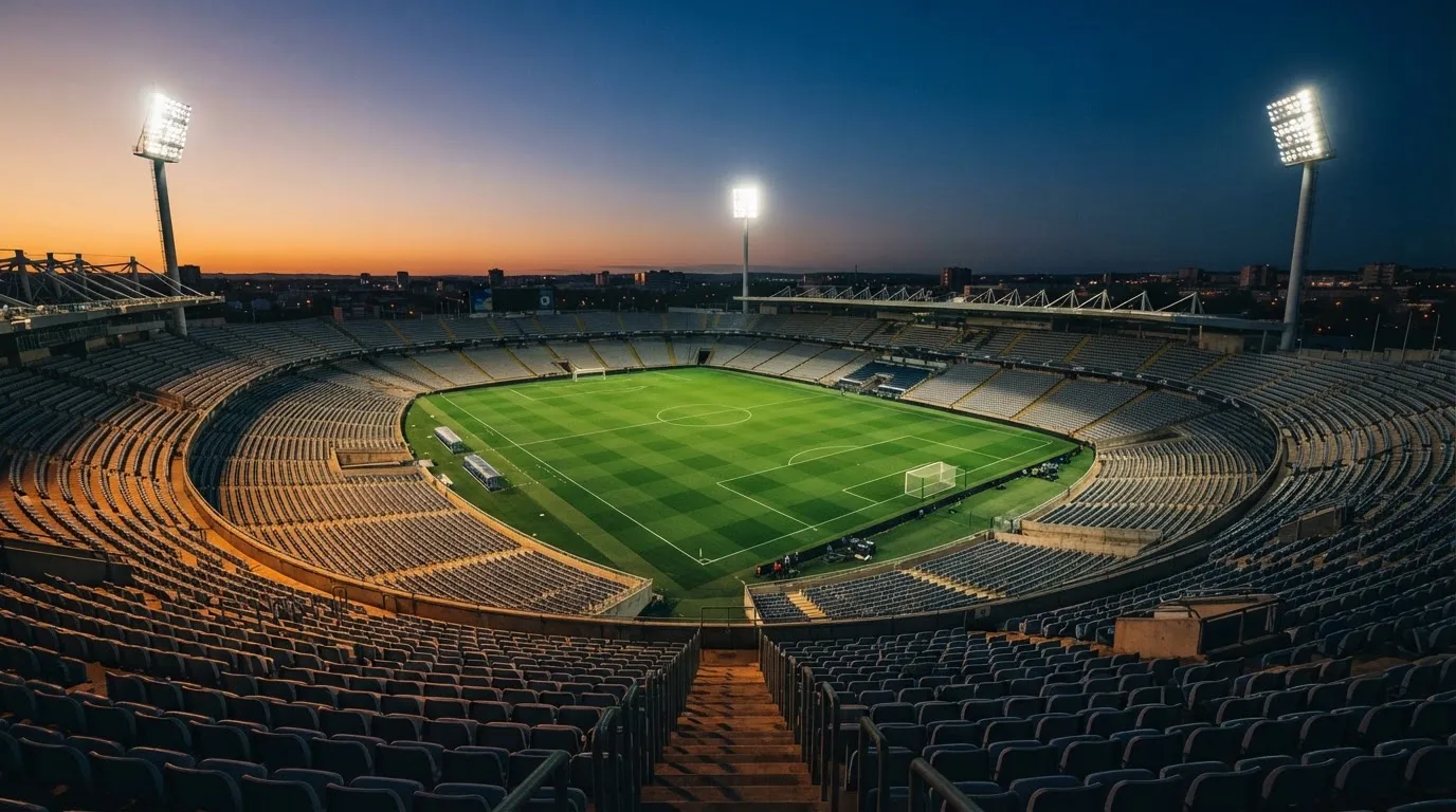 An empty football stadium with floodlight masts at dusk