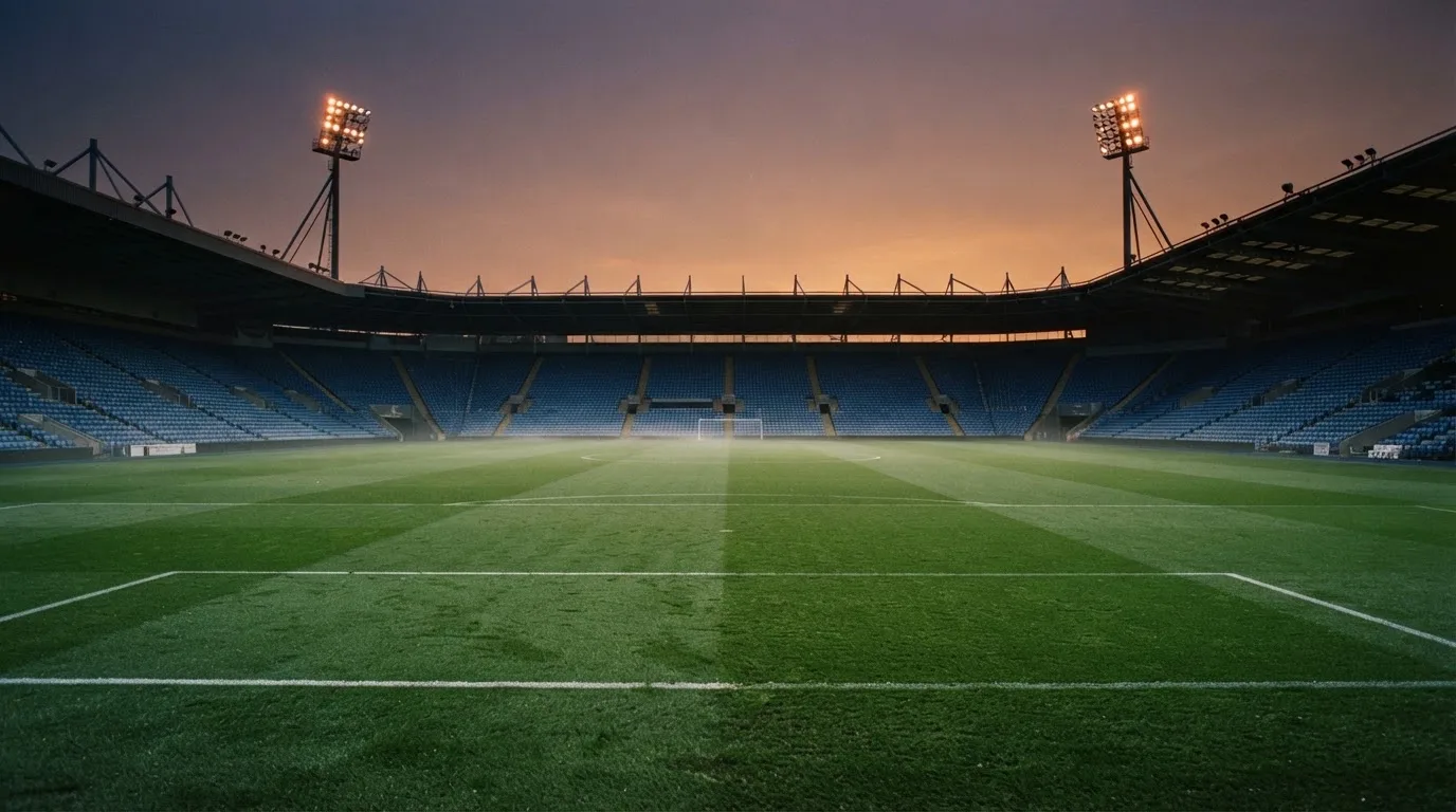 An empty football stadium with floodlight masts at dusk