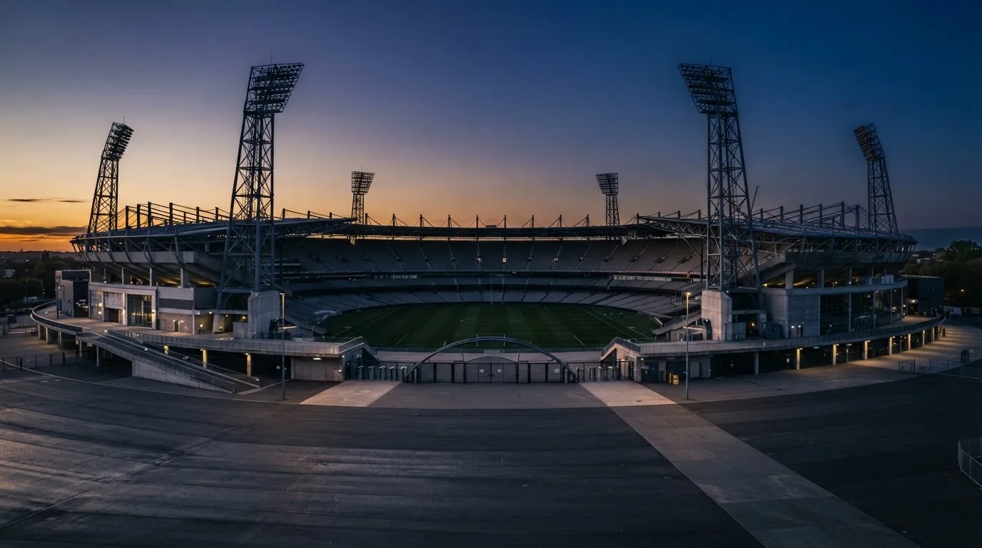 An empty football stadium with floodlight masts at dusk