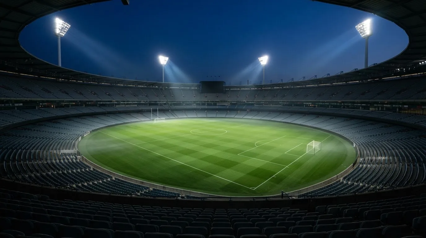 An empty football stadium with floodlight masts at dusk