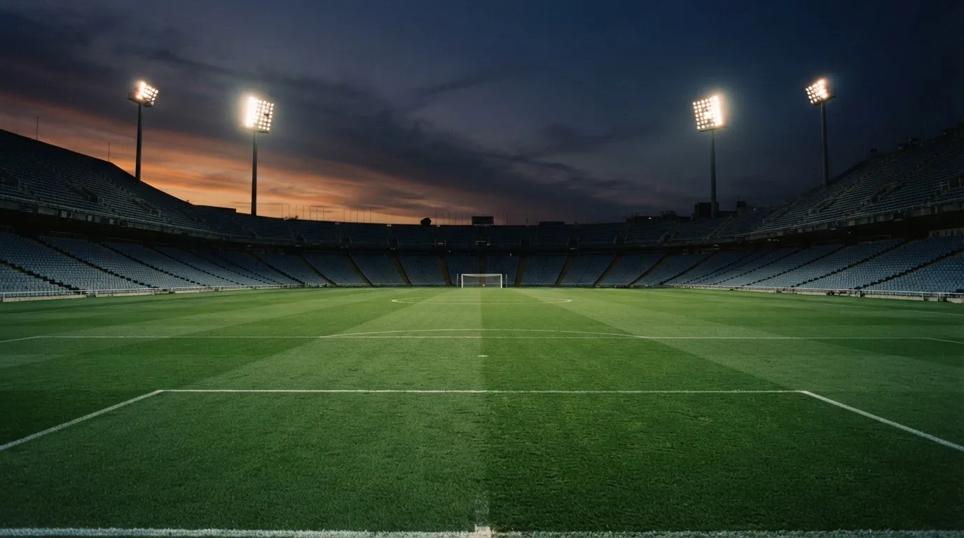 An empty football stadium with floodlight masts at dusk