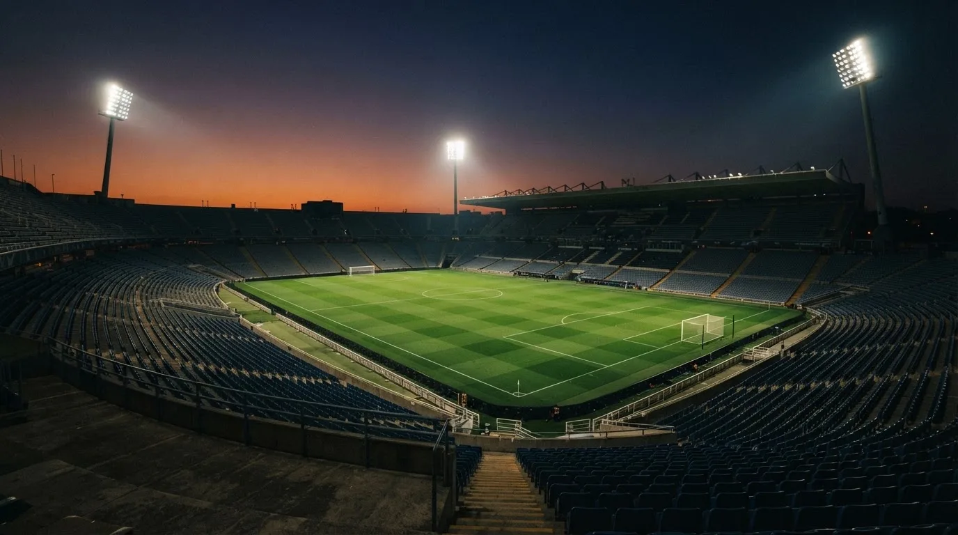 An empty football stadium with floodlight masts at dusk