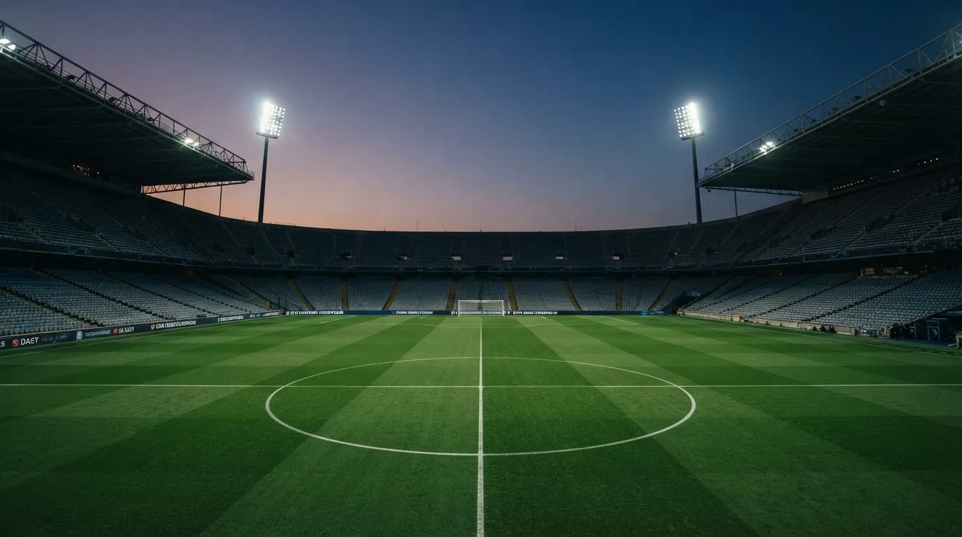 An empty football stadium with floodlight masts at dusk
