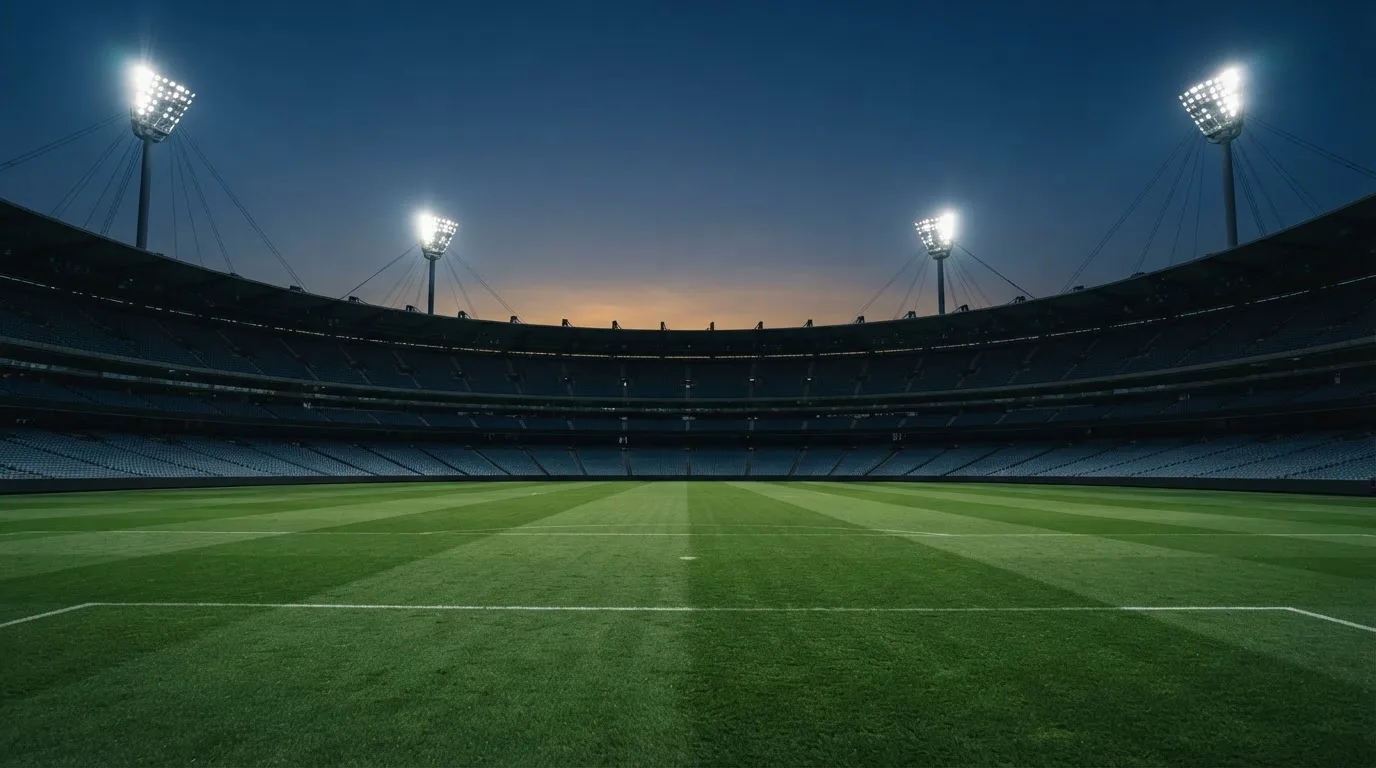 An empty football stadium with floodlight masts at dusk
