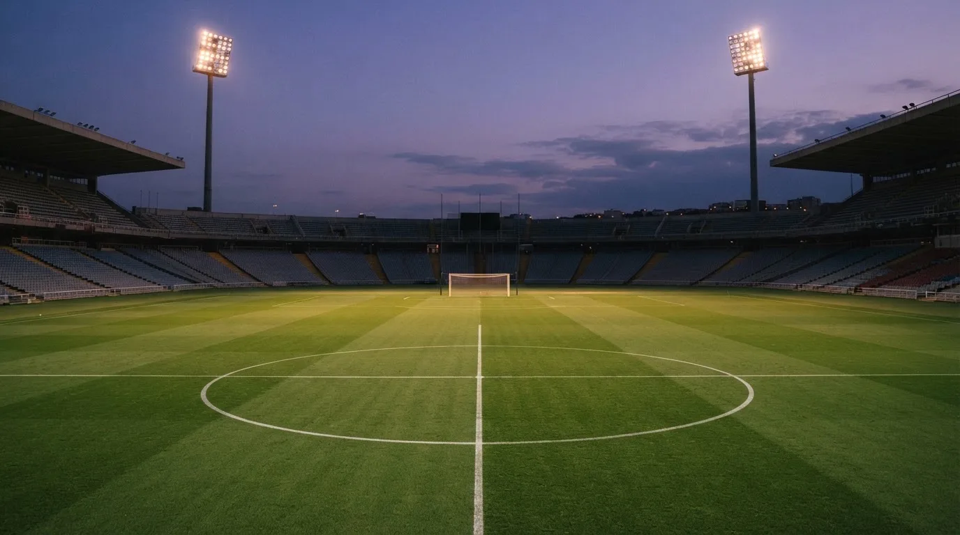 An empty football stadium with floodlight masts at dusk