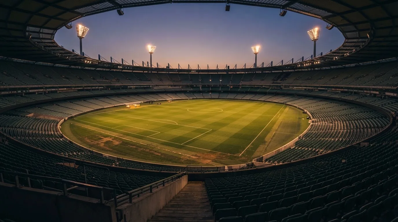 An empty football stadium with floodlight masts at dusk