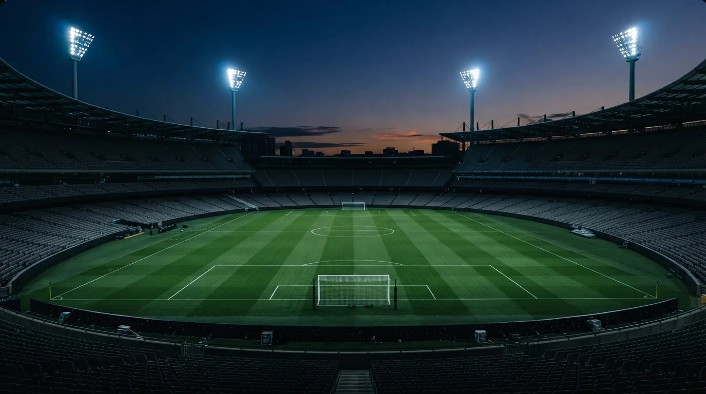 An empty football stadium with floodlight masts at dusk