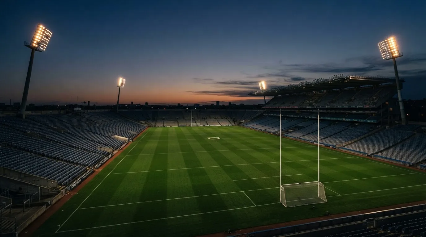 An empty football stadium with floodlight masts at dusk