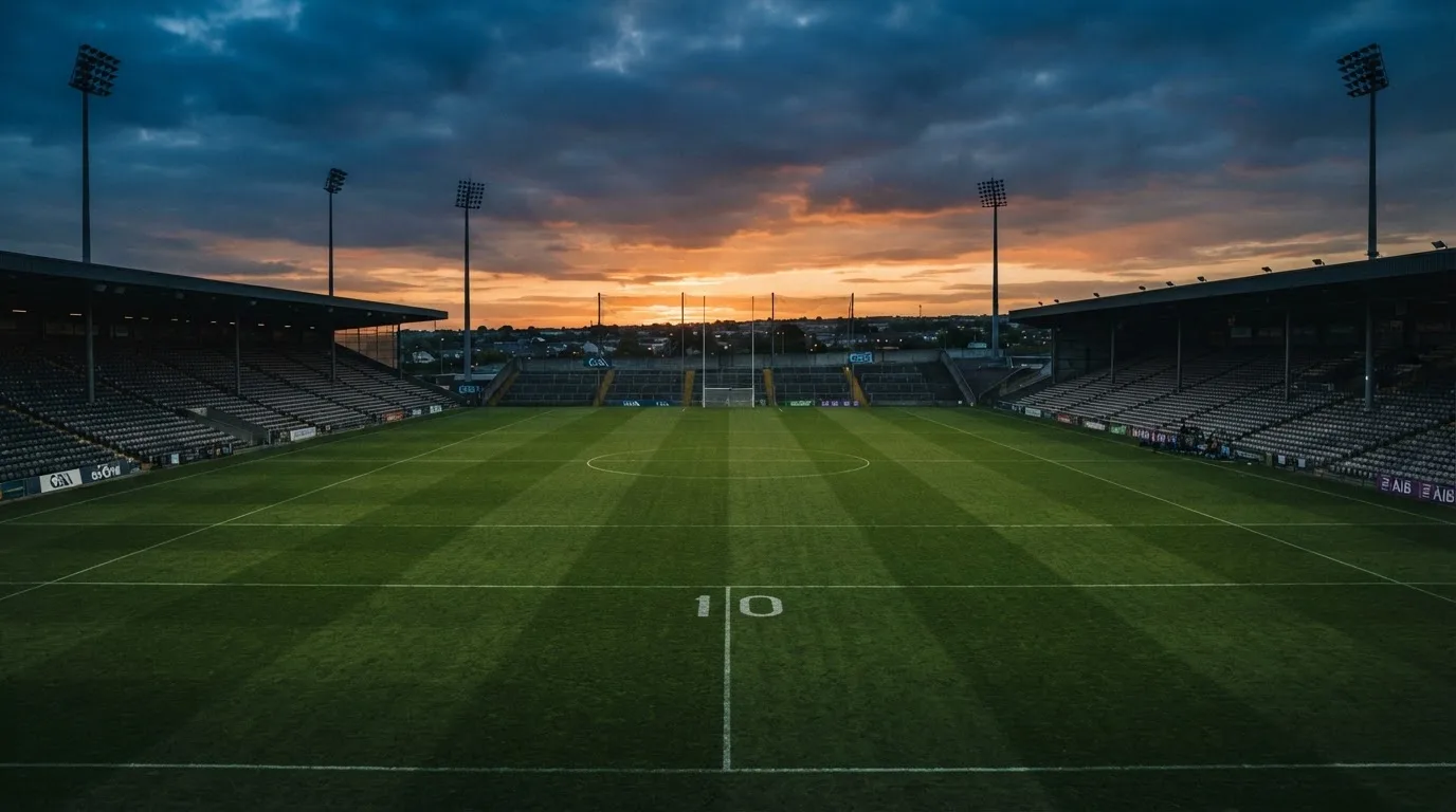 An empty football stadium with floodlight masts at dusk
