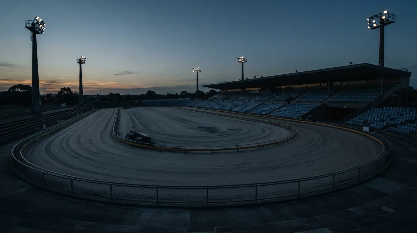 An empty football stadium with floodlight masts at dusk