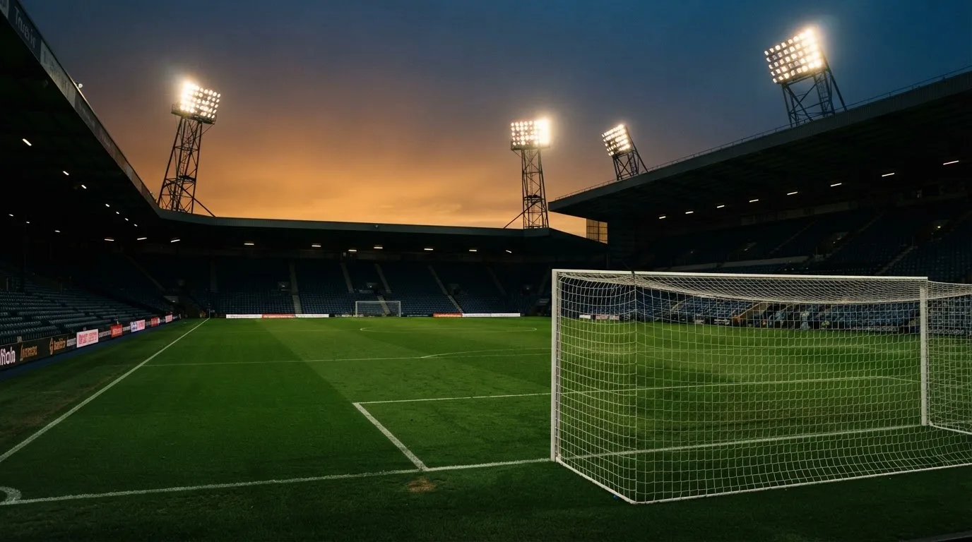 An empty football stadium with floodlight masts at dusk