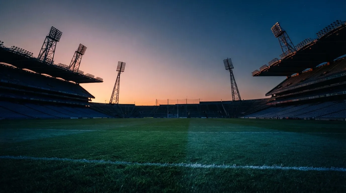 An empty football stadium with floodlight masts at dusk