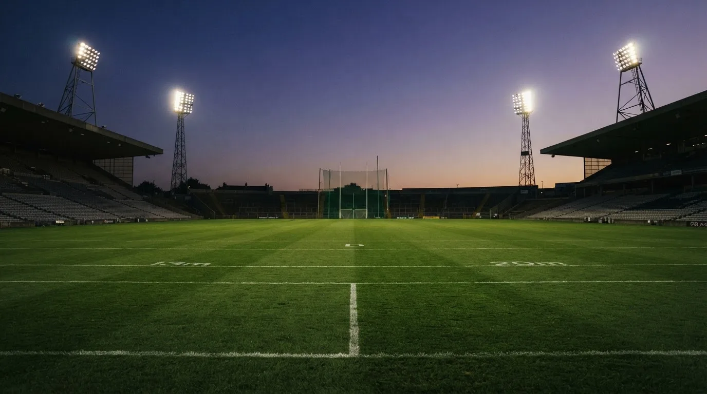 An empty football stadium with floodlight masts at dusk