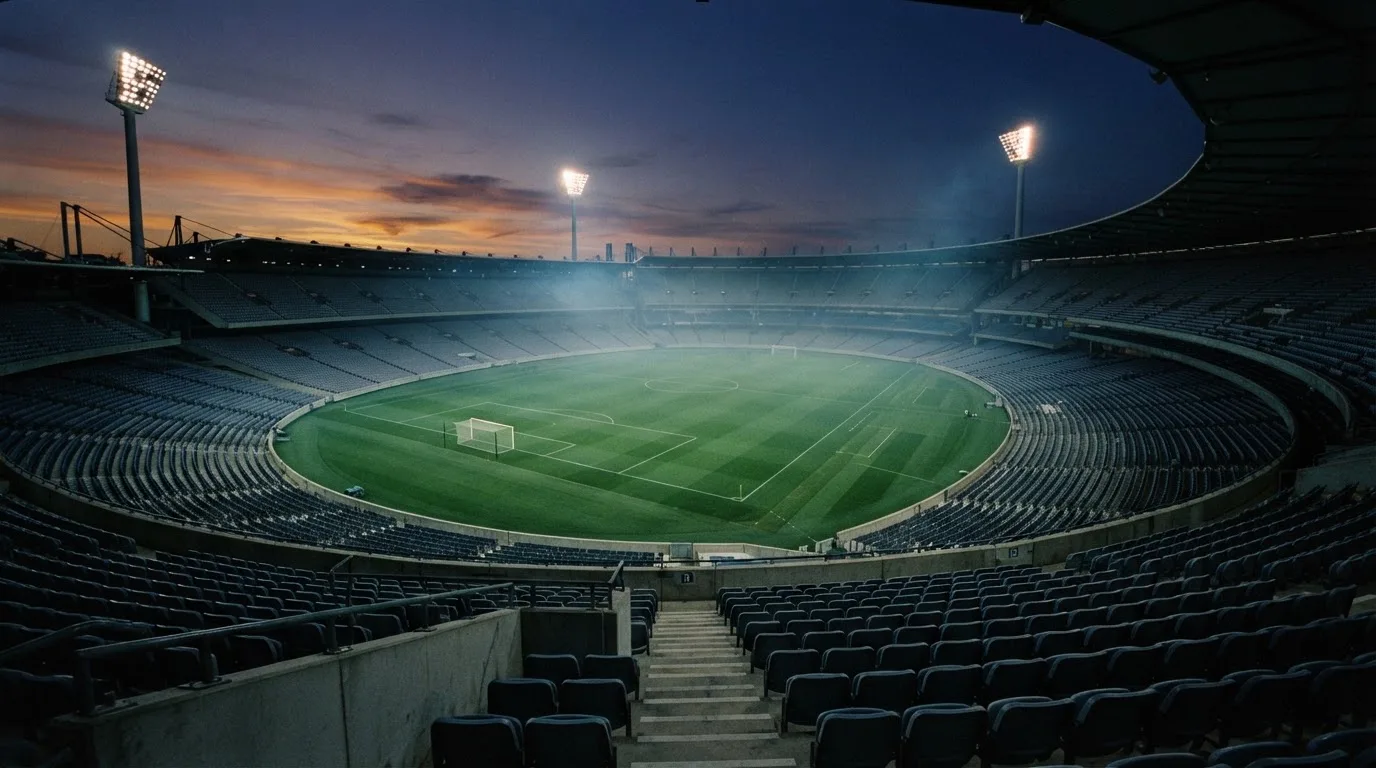 An empty football stadium with floodlight masts at dusk