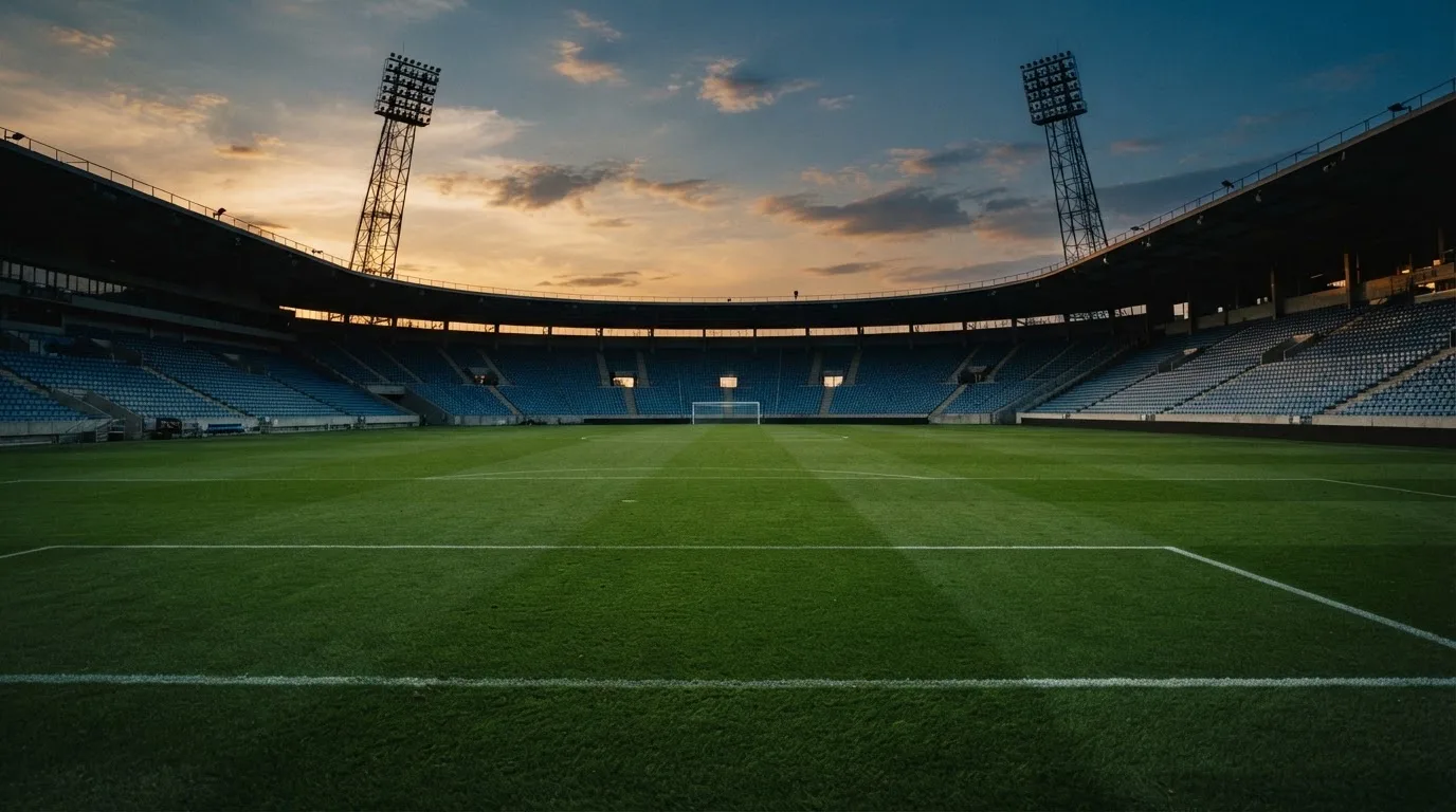 An empty football stadium with floodlight masts at dusk