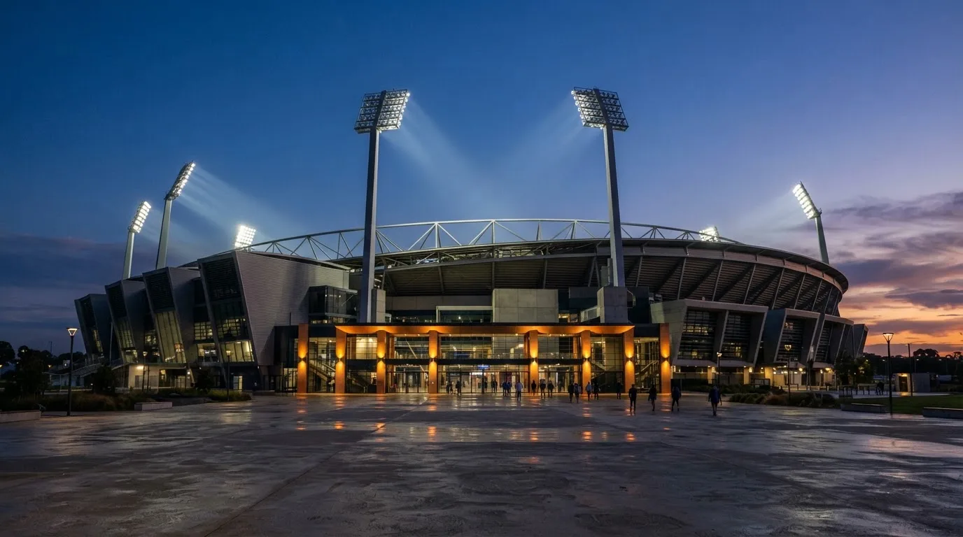 An empty football stadium with floodlight masts at dusk