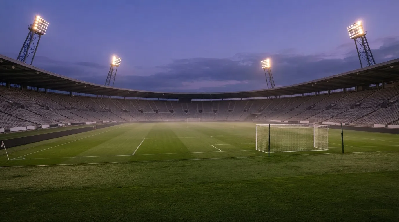 An empty football stadium with floodlight masts at dusk