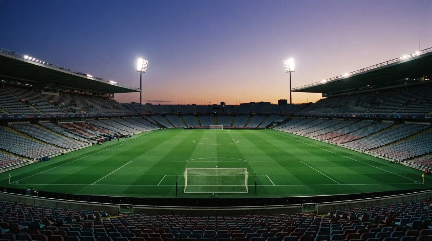An empty football stadium with floodlight masts at dusk