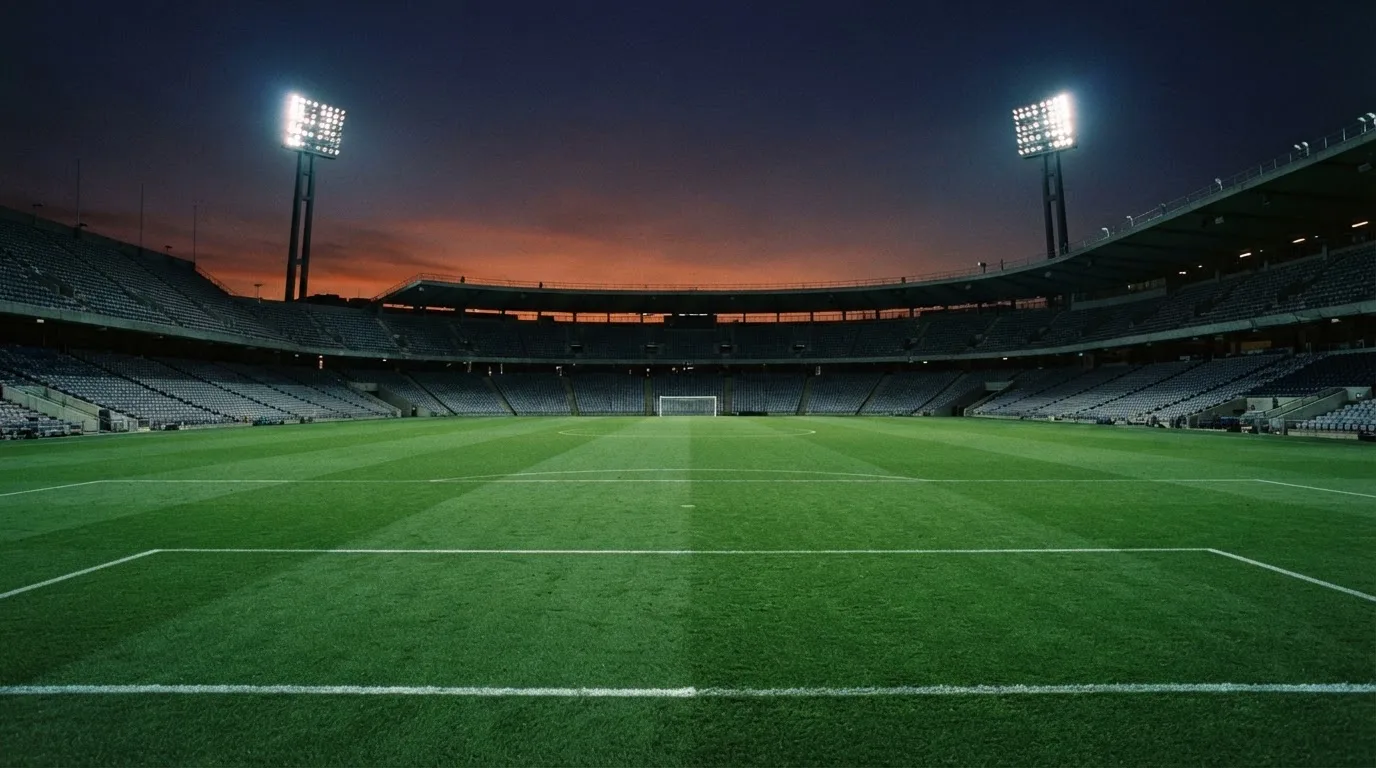 An empty football stadium with floodlight masts at dusk