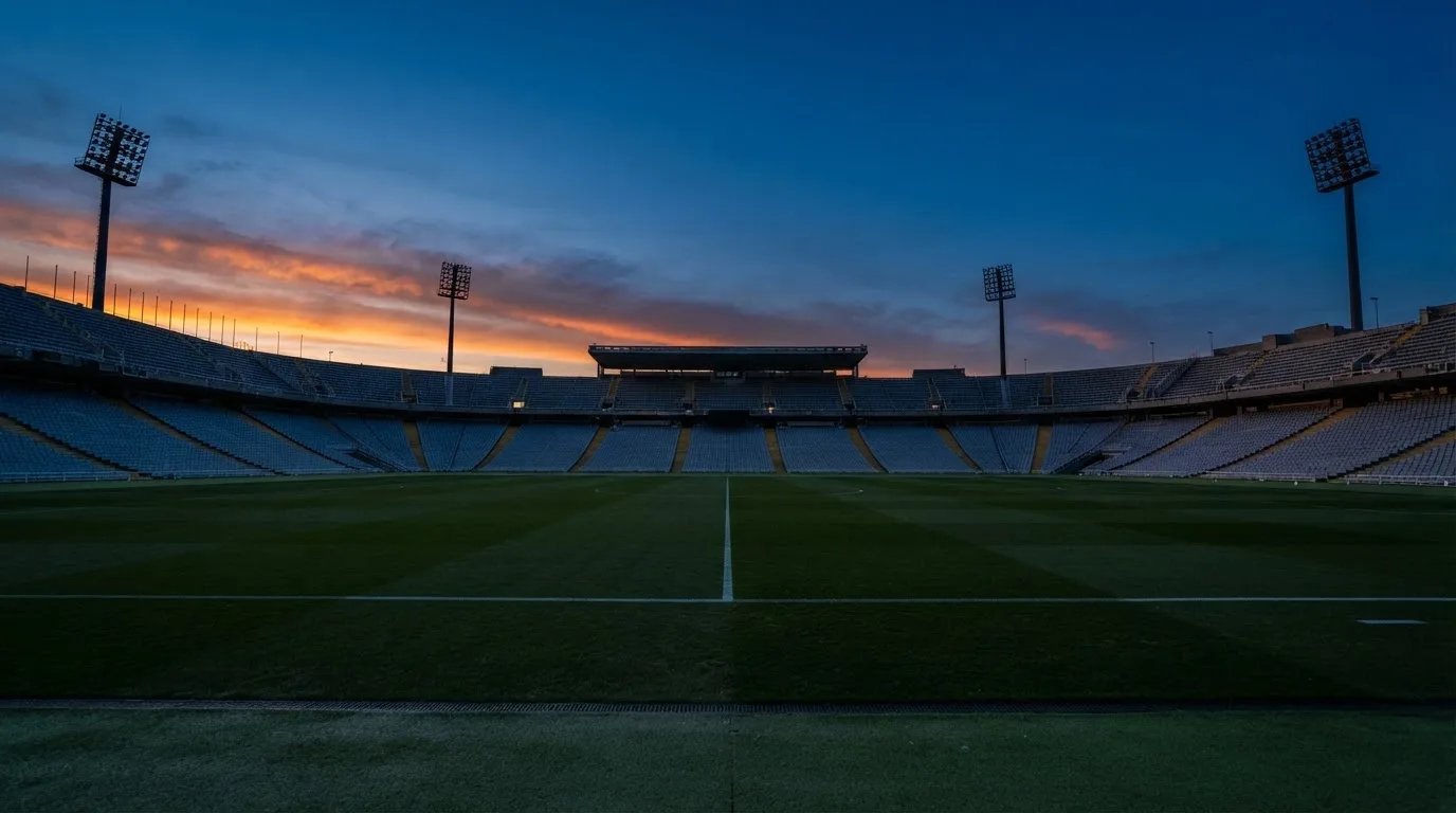 An empty football stadium with floodlight masts at dusk
