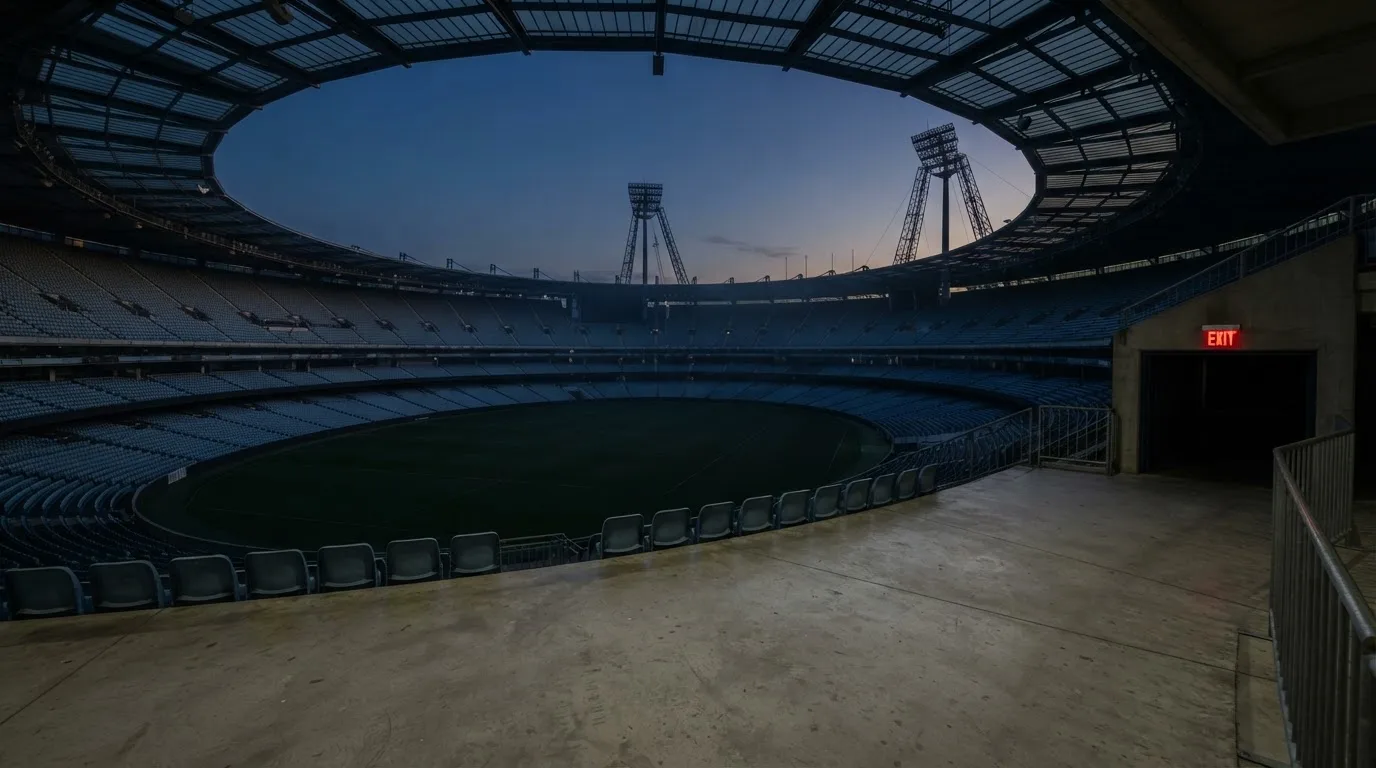An empty football stadium with floodlight masts at dusk