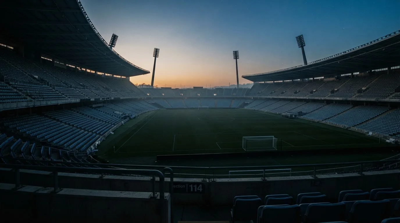 An empty football stadium with floodlight masts at dusk