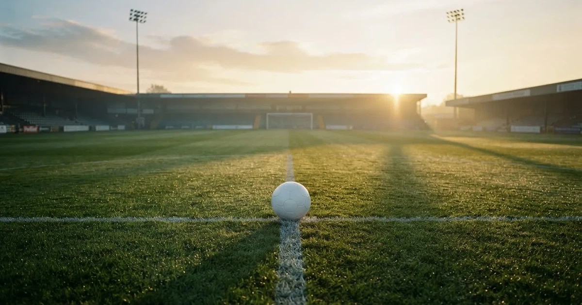 A ball on the centre spot of a grass pitch in morning light