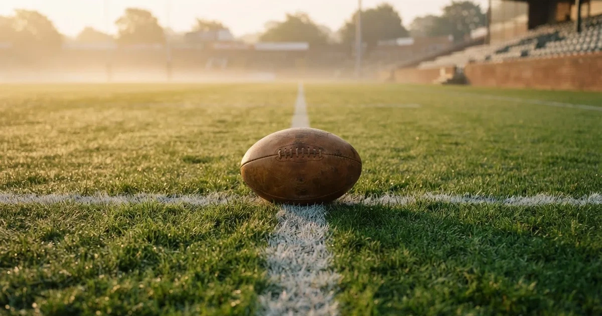 A ball on the centre spot of a grass pitch in morning light