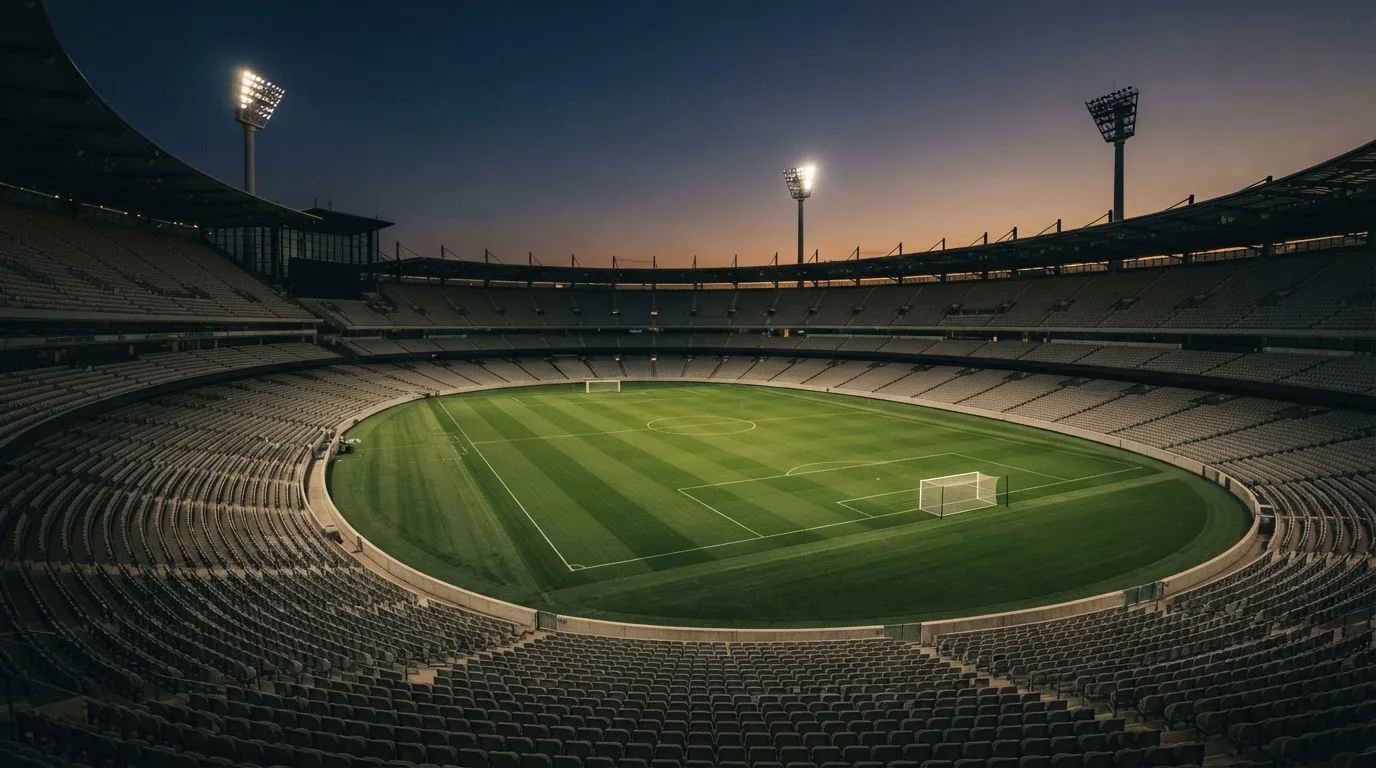 An empty football stadium with floodlight masts at dusk