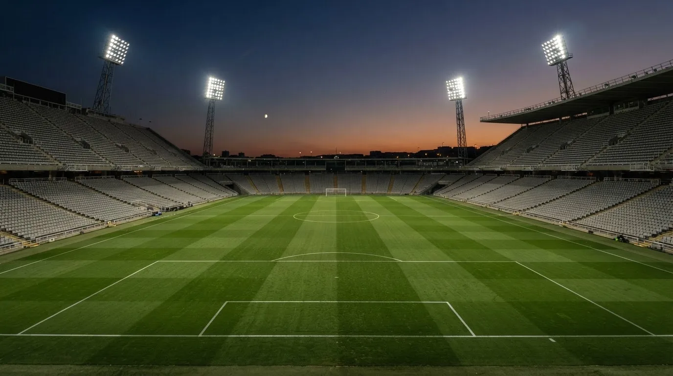 An empty football stadium with floodlight masts at dusk