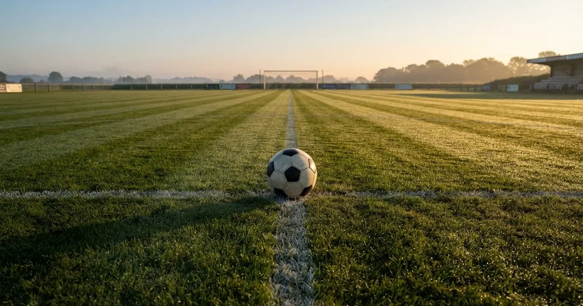 A ball on the centre spot of a grass pitch in morning light