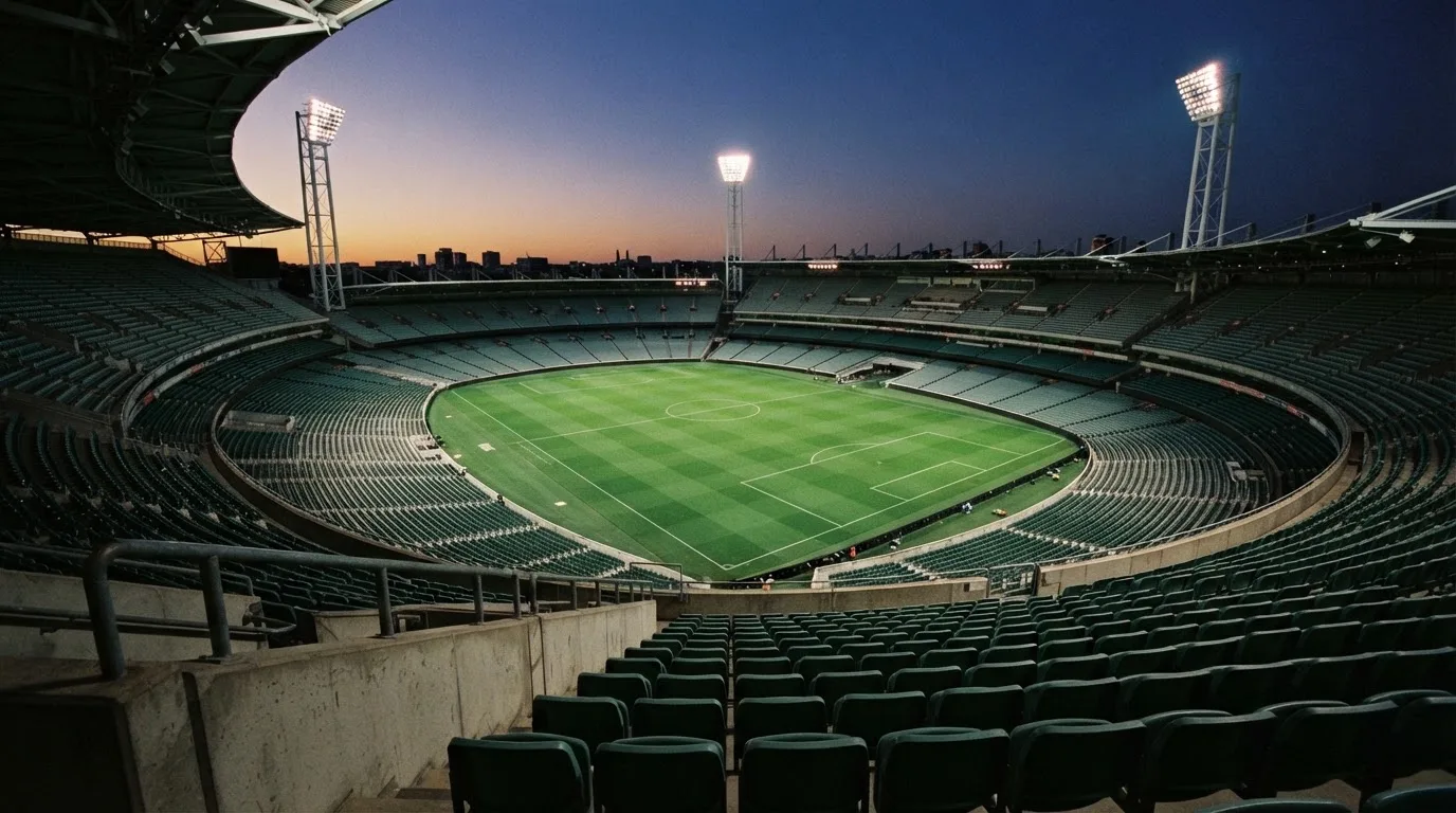 An empty football stadium with floodlight masts at dusk
