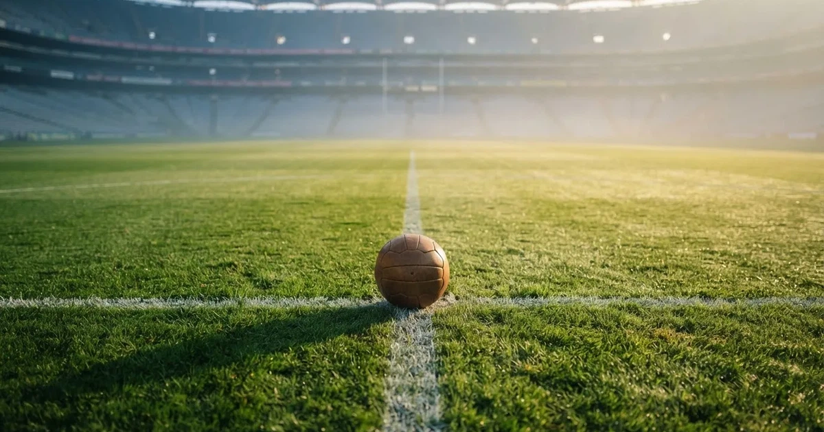 A ball on the centre spot of a grass pitch in morning light