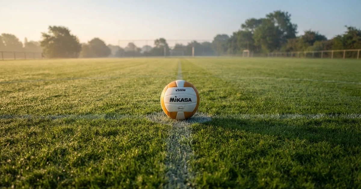 A ball on the centre spot of a grass pitch in morning light