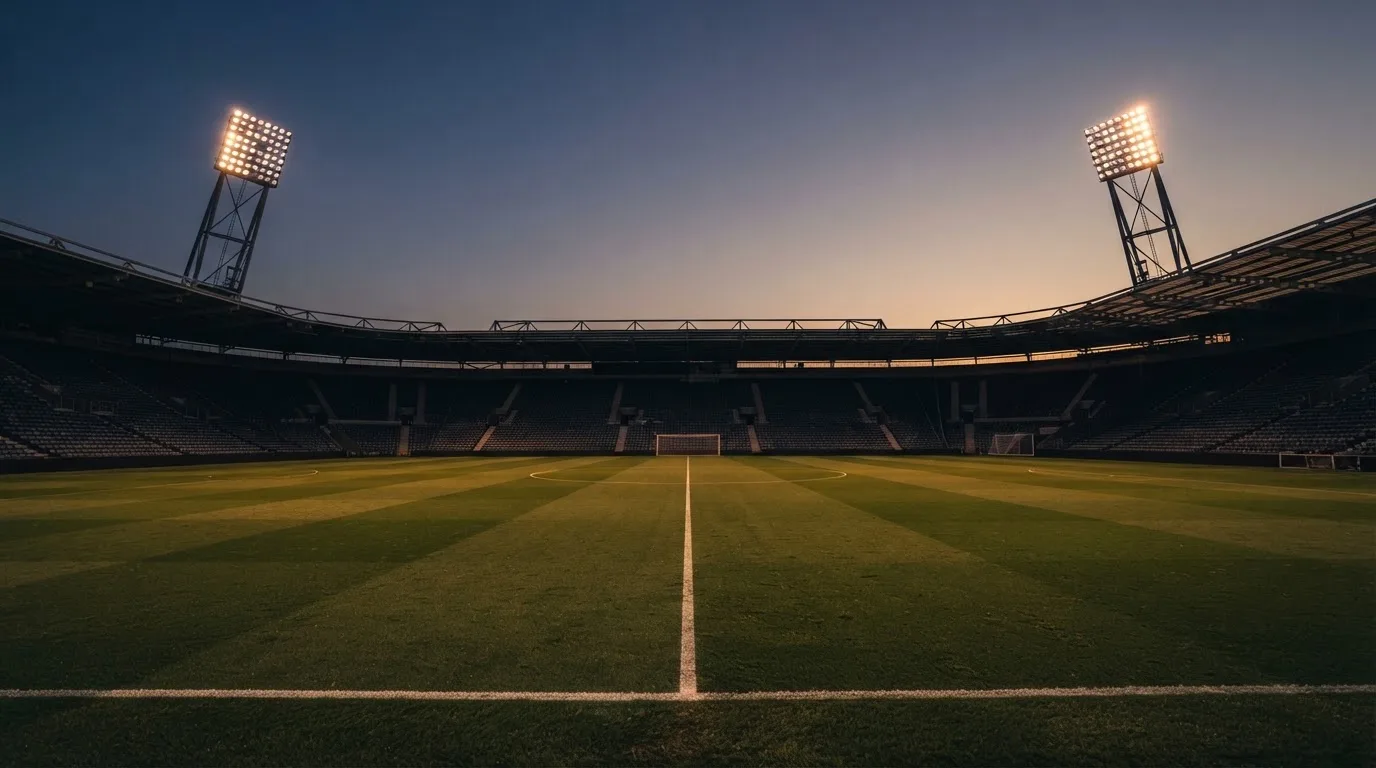 An empty football stadium with floodlight masts at dusk