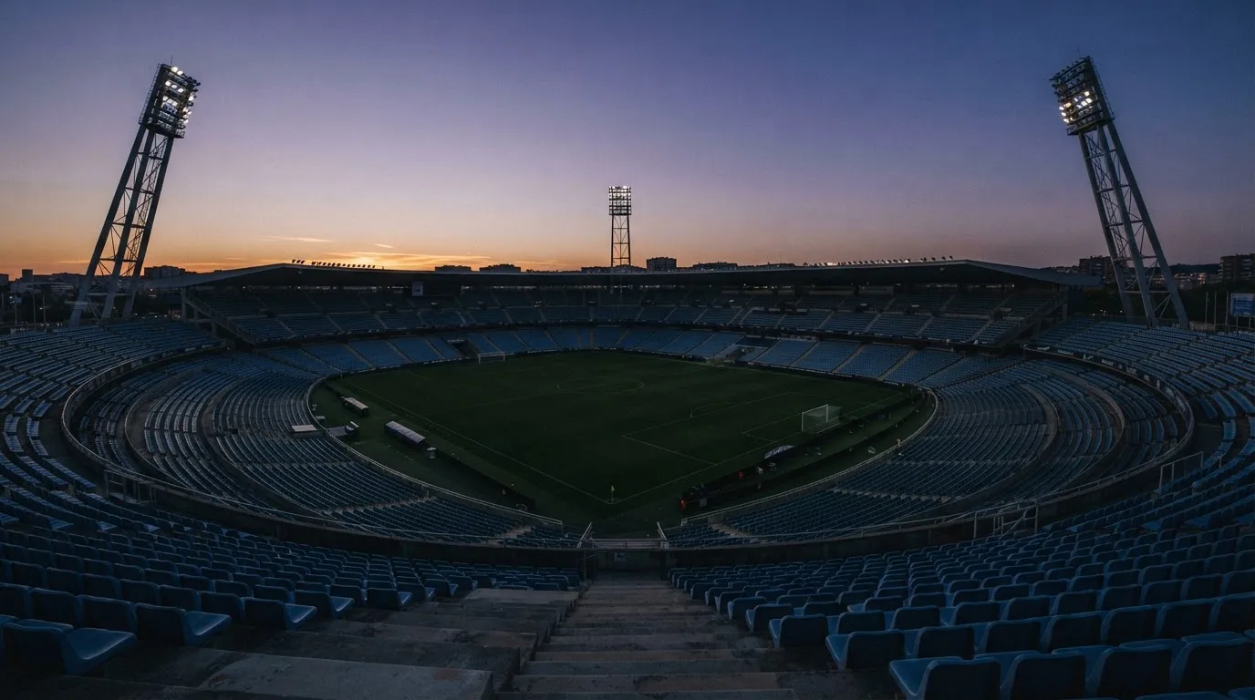 An empty football stadium with floodlight masts at dusk